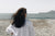 femme-de-dos-qui-admire-la-mer-sur-une-plage-de-galets