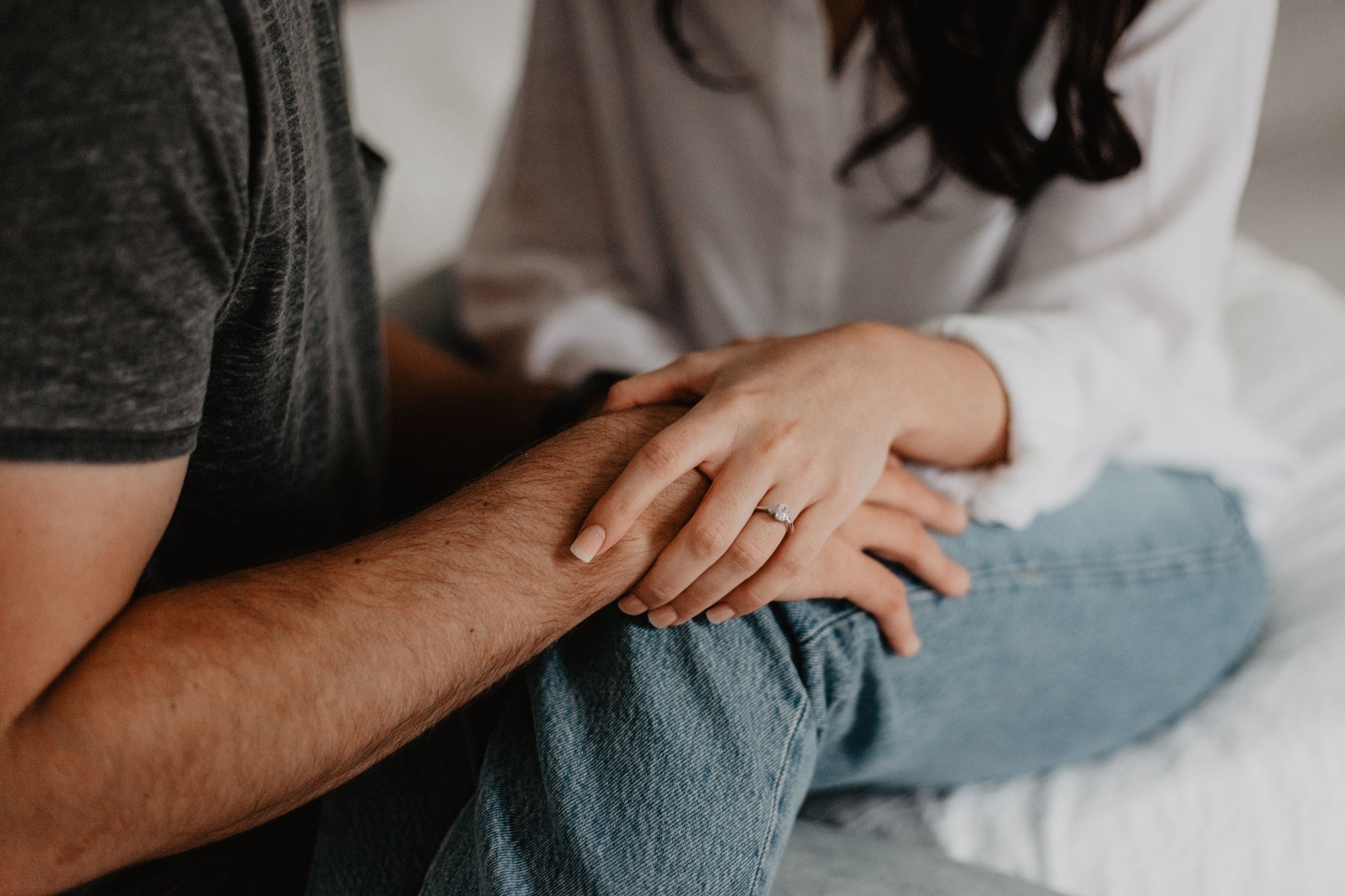 femme assise sur un lit et qui tient tendrement le bras de son mari à côté d'elle