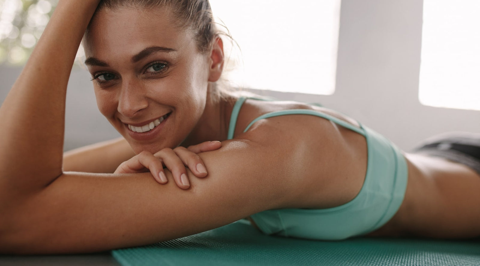 femme-souriante-avec-une-tenue-de-sport-bleue-sur-un-tapis-sport