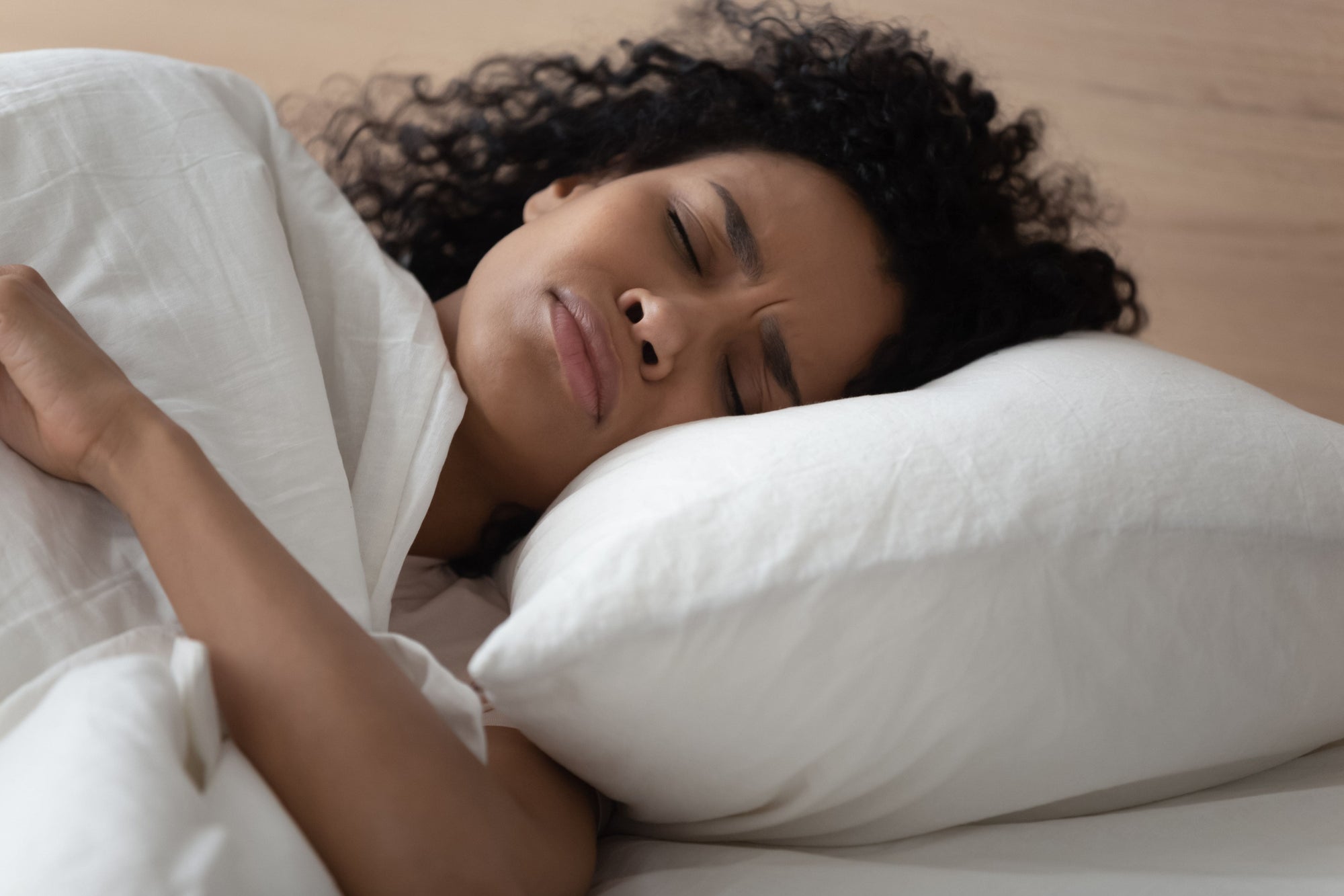 femme-qui-est-couchee-dans-un-lit-avec-sa-tete-qui-repose-sur-un-oreiller-blanc-et-qui-a-du-mal-a-dormir
