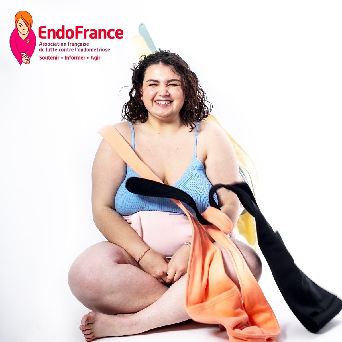 femme-assise-qui-sourit-avec-plusieurs-ceintures-bouillottes-sur-elle